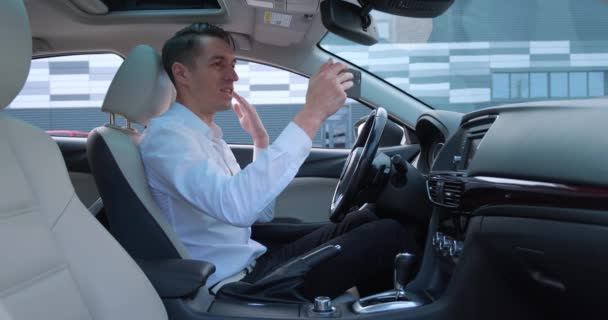 Jovem empresário ter vídeo chat usando smartphone enquanto sentado em um carro. Motorista masculino falando videochamada no celular. - Filmagem, Vídeo