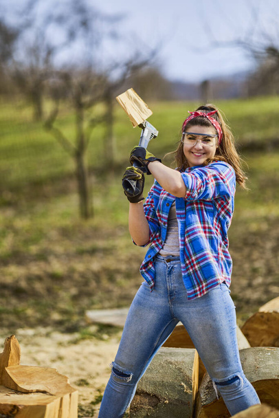 Γυναικεία ξυλεία σπάει κούτσουρα οξιάς με ένα μεγάλο τσεκούρι. - Φωτογραφία, εικόνα
