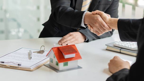 Agente de bienes raíces da la mano con el cliente después de firmar el acuerdo de compra de una casa después de que Finan ha pasado. - Foto, Imagen