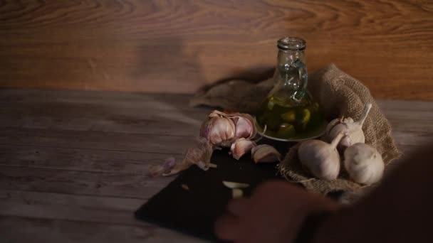 Video einer Person, die Knoblauch hackt und in Olivenöl gibt, um ein aromatisches Knoblauchöl als Gewürz für Lebensmittel und natürliche Therapien herzustellen. - Filmmaterial, Video