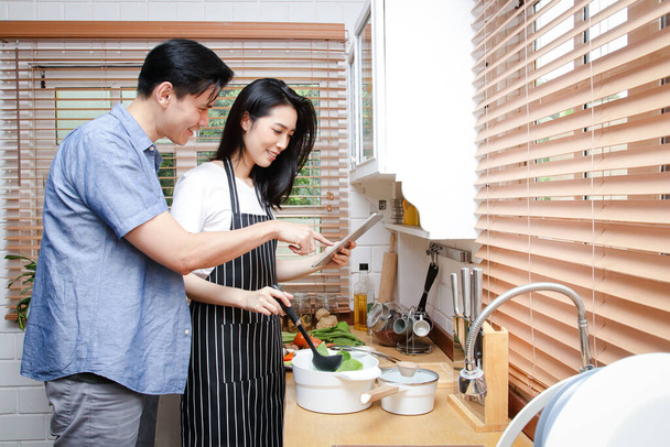 Las parejas asiáticas cocinan juntas en sus cocinas caseras. Living Concept During Covid-19, Distancia social, espacio de copia - Foto, imagen