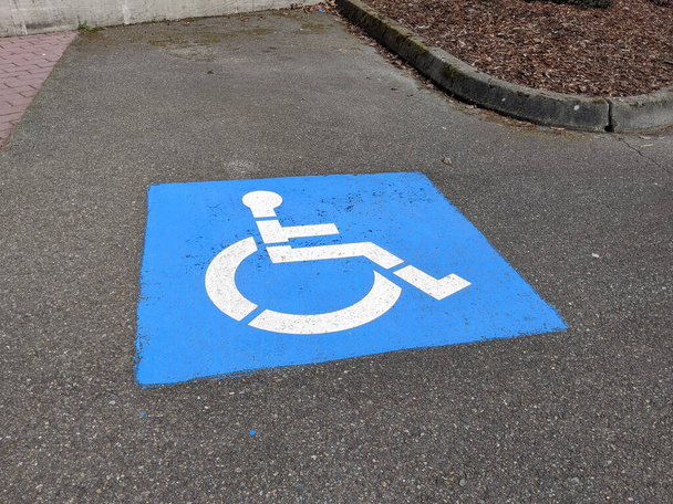 Vista ad alto angolo di un'icona handicap in un parcheggio in un terreno pavimentato all'aperto - Foto, immagini