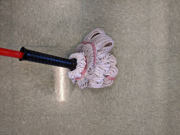 Close up of a wet mop soaping up a tiled floor in a medical building, santizing the area of germs - Photo, Image