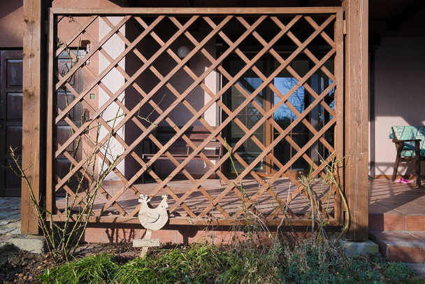 Madera, calado, pérgola marrón que protege una terraza de la casa rural  - Foto, imagen