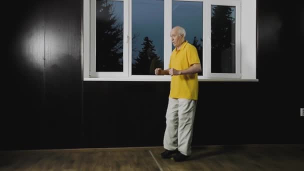 Vanha mies urheilija kouluttaa liikettä telineessä ikkunan vieressä - Materiaali, video