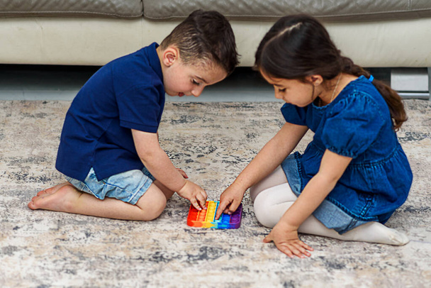 Dwa słodkie dzieci gra z elastyczną zabawką Pop To fidget. - Zdjęcie, obraz
