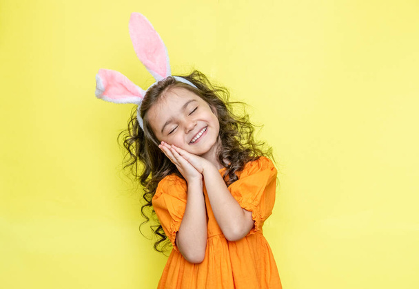 смішна щаслива дівчина з великодніми вухами кролика на жовтому фоні
 - Фото, зображення