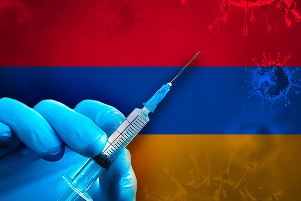Armenia Campagna di vaccinazione Covid-19. Una mano in un guanto di gomma blu tiene una siringa con vaccino antivirale covid-19 davanti alla bandiera armena. Concetto di vaccinazione contro il coronavirus - Foto, immagini