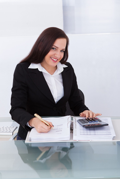 Glückliche Geschäftsfrau bei der Steuerberechnung - Foto, Bild
