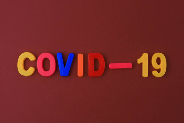 Uma palavra ou texto Covid-19 escrito em um alfabeto infantil com letras clássicas em um ímã. - Foto, Imagem