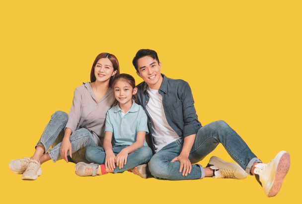 Heureuse jeune famille asiatique avec un enfant assis et souriant à la caméra  - Photo, image