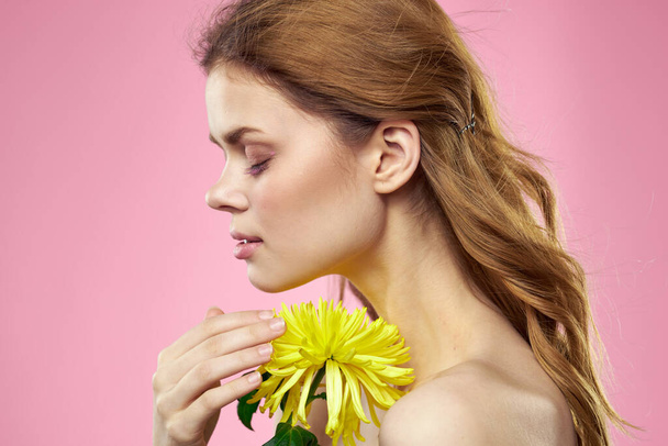 Portrait of a woman with yellow flowers on a pink background Makeup on the face - Photo, image