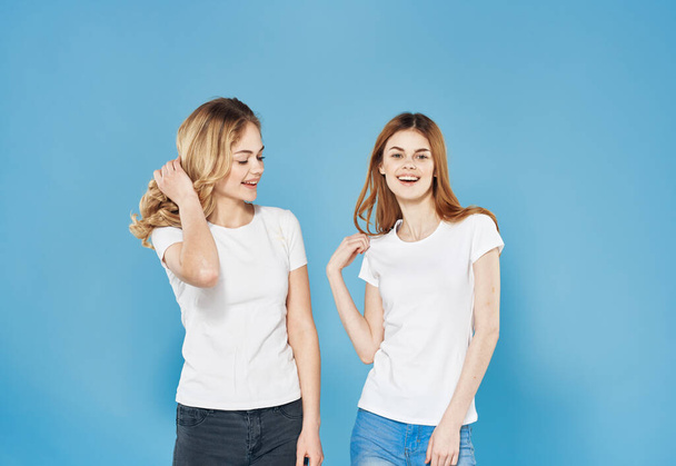 Dos mujeres en camisetas blancas emociones amistosas estilo de vida comunicación fondo azul - Foto, Imagen