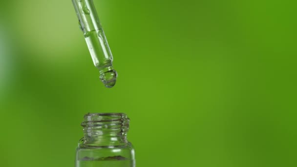 Капля органического эфирного масла падает с пипетки в стеклянную бутылку - Кадры, видео