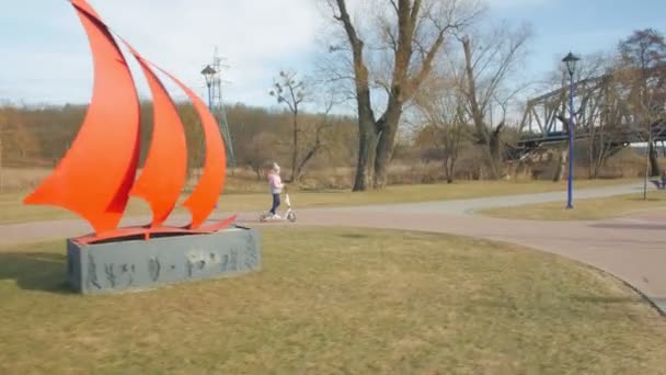 女の子は公園でキックスクーターに乗る - 映像、動画