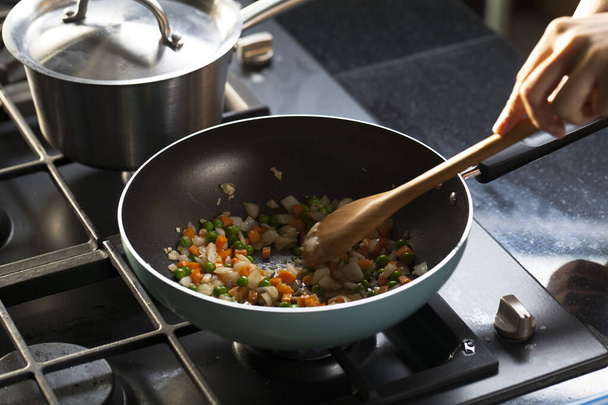 Mezcla de ingredientes vegetales que se cocinan en una sartén frita en una estufa, cocinar en una estufa. - Foto, imagen