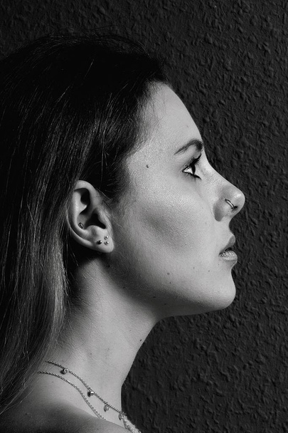 Πορτραίτο προφίλ μιας όμορφης νεαρής γυναίκας με σκουλαρίκι στη μύτη σε μαύρο και άσπρο - Φωτογραφία, εικόνα