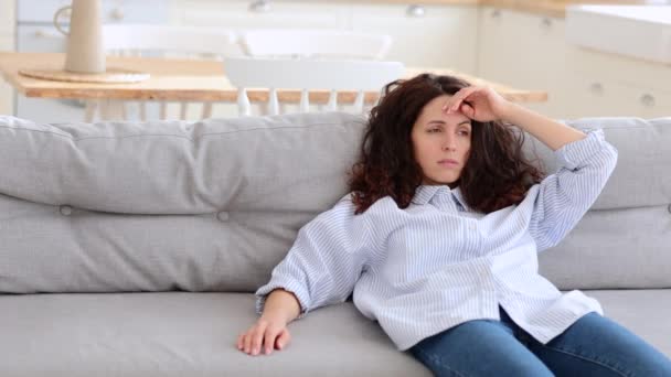 Mujer joven estresada agotada acostada en el sofá en casa se siente abrumada. Fatiga, concepto de exceso de trabajo. - Metraje, vídeo