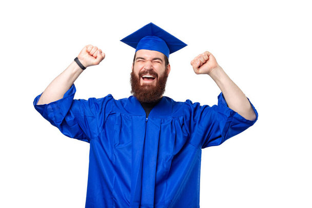 Verbazingwekkende student man dragen van bachelor en afstuderen cap vieren succes. - Foto, afbeelding