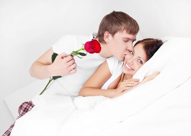 Young man kissing his beautiful girlfriend and giving her a rose - Foto, Imagen