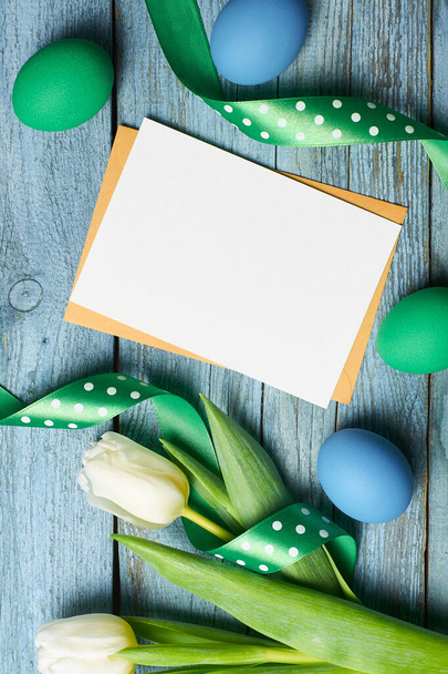 Easter holiday greeting card with tulips flowers and colored eggs over wooden background - Valokuva, kuva