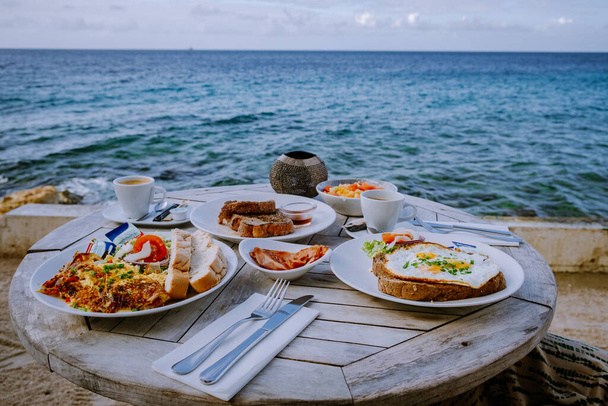 Breakfast by the ocean on the beach looking out over ocean, scrambled egg and fruit - Photo, Image
