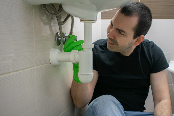 The main subject is out of focus, Solving Common Household Drain Problems, symptoms Solutions blockage male man sit floor unhappy tired sink pipe bathroom repair slow draining - Photo, Image