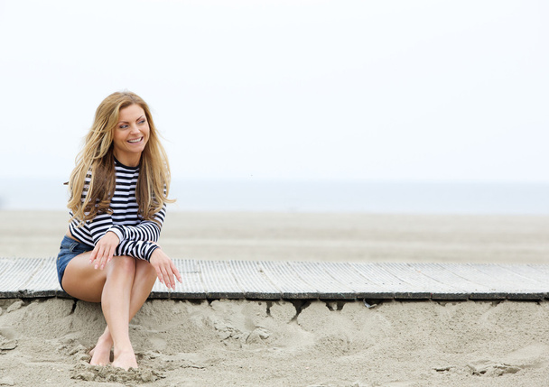 Souriante jeune femme blonde assise à la plage
  - Photo, image