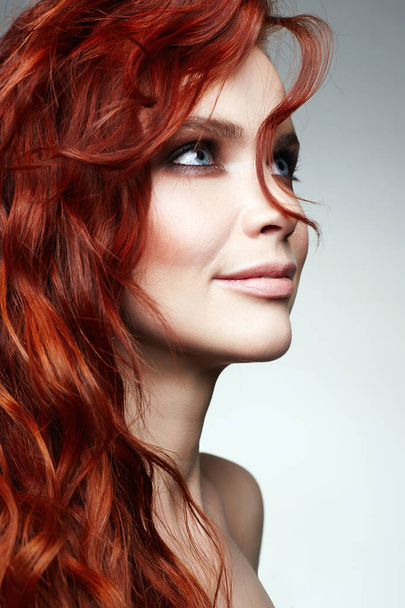 όμορφη ευτυχισμένη γυναίκα με σγουρά κόκκινα μαλλιά και μακιγιάζ. πορτρέτο ομορφιά της υγιή μαλλιά χαμογελαστό κορίτσι - Φωτογραφία, εικόνα