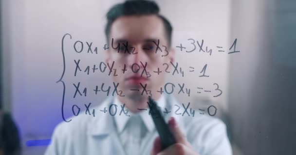 Mannelijke wetenschapper denkt na over de oplossing van de vergelijking, getekend op een glazen bord in een laboratorium. De wiskundige lost het probleem op. - Video