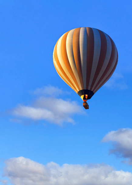 Объемный воздушный шар в свете солнечных лучей поднимает корзину с туристами высоко в небо. Пламя огня нагревает воздух в воздушном шаре. Вертикальное изображение, крупный план, пространство для копирования. - Фото, изображение