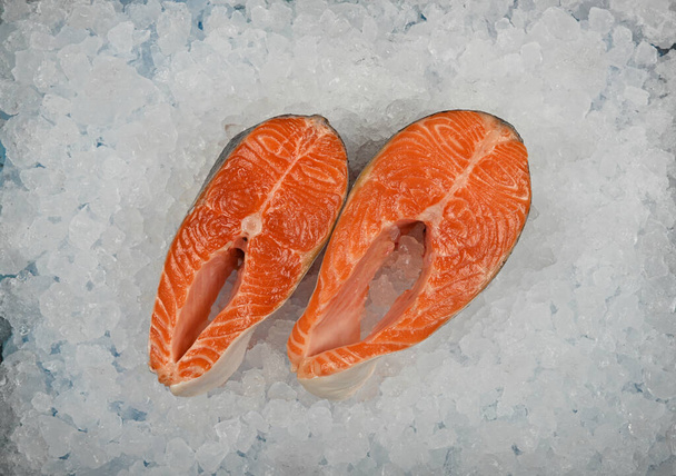 Feche dois bifes de peixe de salmão cru frescos no fundo de gelo picado na exposição de varejo, vista superior elevada, diretamente acima - Foto, Imagem