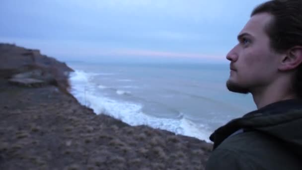 Close shot from a backside of troubled young guy hiking on a coastline alone - Footage, Video