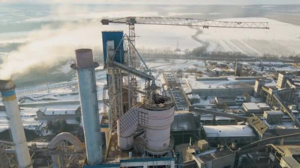 Vista aérea de la planta de cemento con estructura de fábrica alta y grúa torre en el área de producción industrial al atardecer. - Imágenes, Vídeo