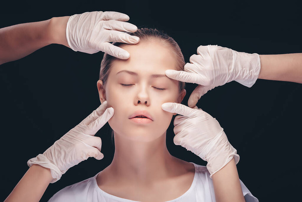 Young woman with eyes closed having an medical exam of her face skin by plastic doctors - Fotografie, Obrázek