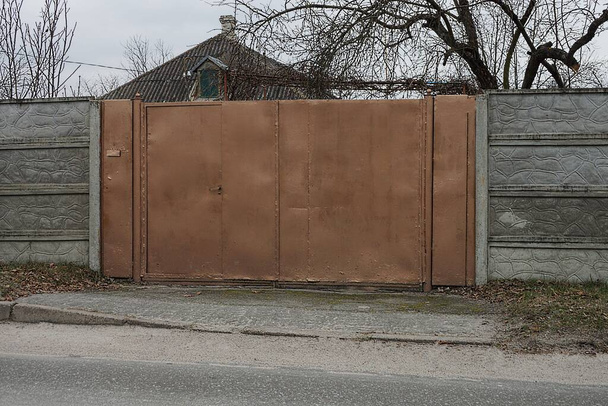 большие коричневые металлические ворота и часть серой бетонной стены снаружи - Фото, изображение