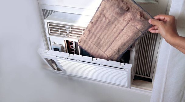 vrouwenhand die de vuile airconditioner thuis filter vasthoudt. Ruimte voor tekst. - Foto, afbeelding