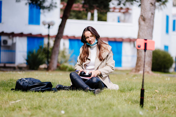 kız öğrenci cep telefonunda sanal öğrenim yüz maskesi takıyor açık havada internet  - Fotoğraf, Görsel