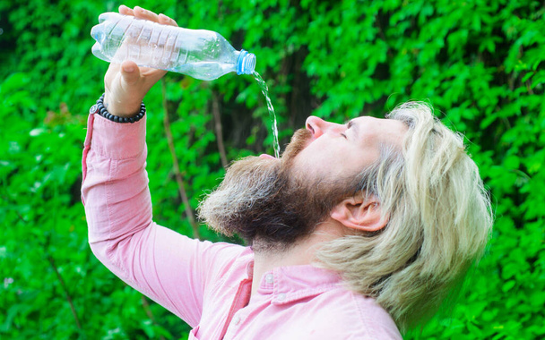 Концепция гидратации. Бородач пьет воду. Мужчина с бутылкой воды. Здоровый образ жизни. - Фото, изображение