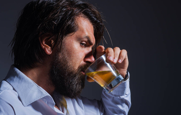 Een man met baard drinkt whisky of Brandy. Sterke alcohol. Degustation en proeverij. Mannelijke dranken cognac. - Foto, afbeelding