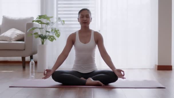Азиатка практикует медитацию йоги дома. - Кадры, видео