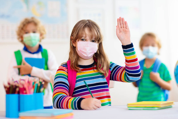 Шкільна дитина носить маску для обличчя під час вірусу корони та спалаху грипу. Хлопчик і дівчинка повертаються до школи після карантину та блокування. Група дітей у масках для профілактики коронавірусу
.  - Фото, зображення