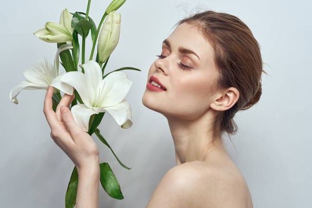Schöne Mädchen mit einem Strauß weißer Blumen auf einem hellen Hintergrund nackte Schultern saubere Haut Frühling - Foto, Bild