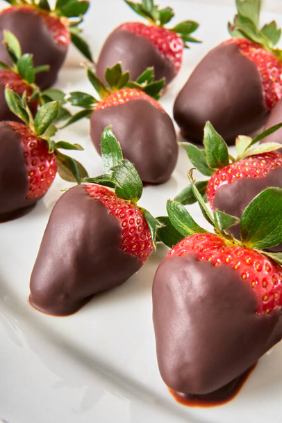 Erdbeeren mit Schokolade überzogen auf einem weißen Teller auf einem Marmortisch. Ausgezeichnetes Geschenk zum Muttertag. - Foto, Bild