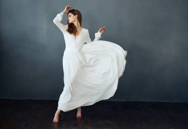 Woman on a gray background in a white dress dance model in full growth - Valokuva, kuva