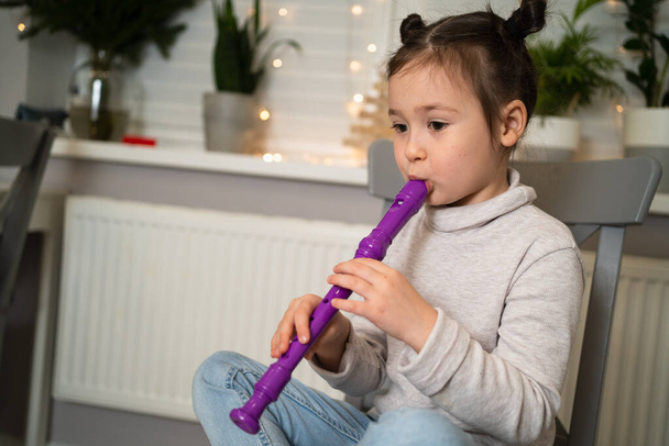 Ένα ταλαντούχο κορίτσι παίζει φλάουτο. Online εκμάθηση για να παίξετε μουσικά όργανα. - Φωτογραφία, εικόνα