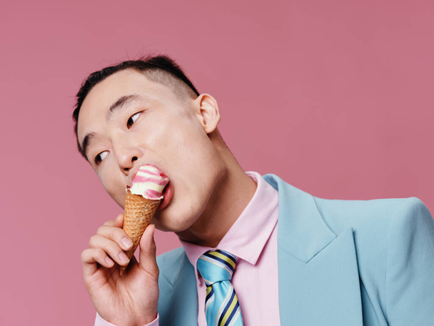 Mies aasialainen ulkonäkö jäätelöä käsissä ruoka ruokavalio vaaleanpunainen tausta  - Valokuva, kuva