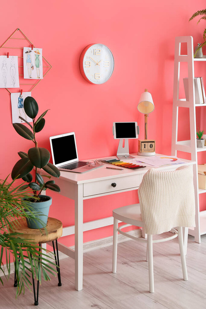 Ofiste renkli duvarın yanında dizüstü bilgisayarı olan şık bir iş yeri - Fotoğraf, Görsel