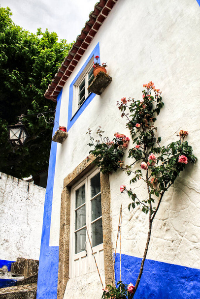 Wąskie i kolorowe uliczki, majestatyczne fasady, okna i balkony starej wioski Obidos, Portugalia - Zdjęcie, obraz