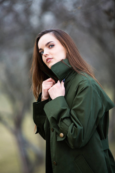 Изображение молодой красивой женщины в дождевой куртке в холодную погоду. Мыслительная европейская девушка в весенней природе. - Фото, изображение